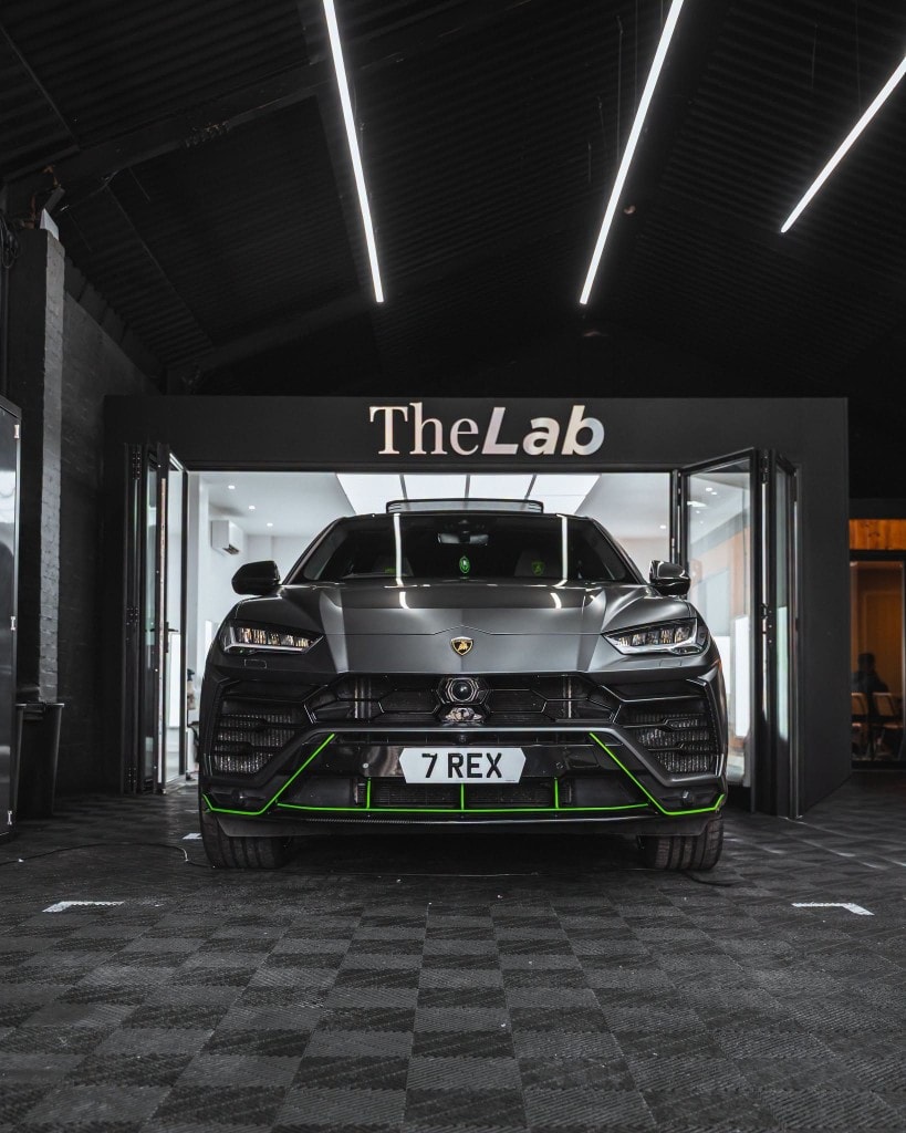 Lamborghini Urus side — matte grey with green pinstripe and carbon