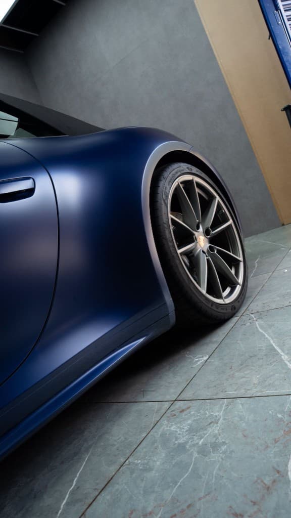 Porsche crest badge mirrored in Night Blue paint — the flawless reflection only detailing achieves
