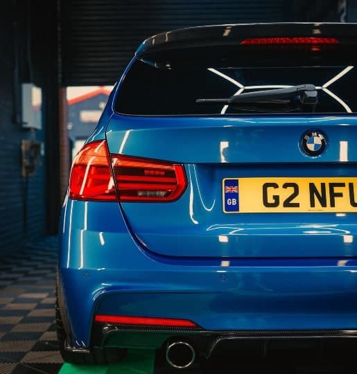 Rear of a blue BMW with freshly fitted dark window tint in the JnJ studio